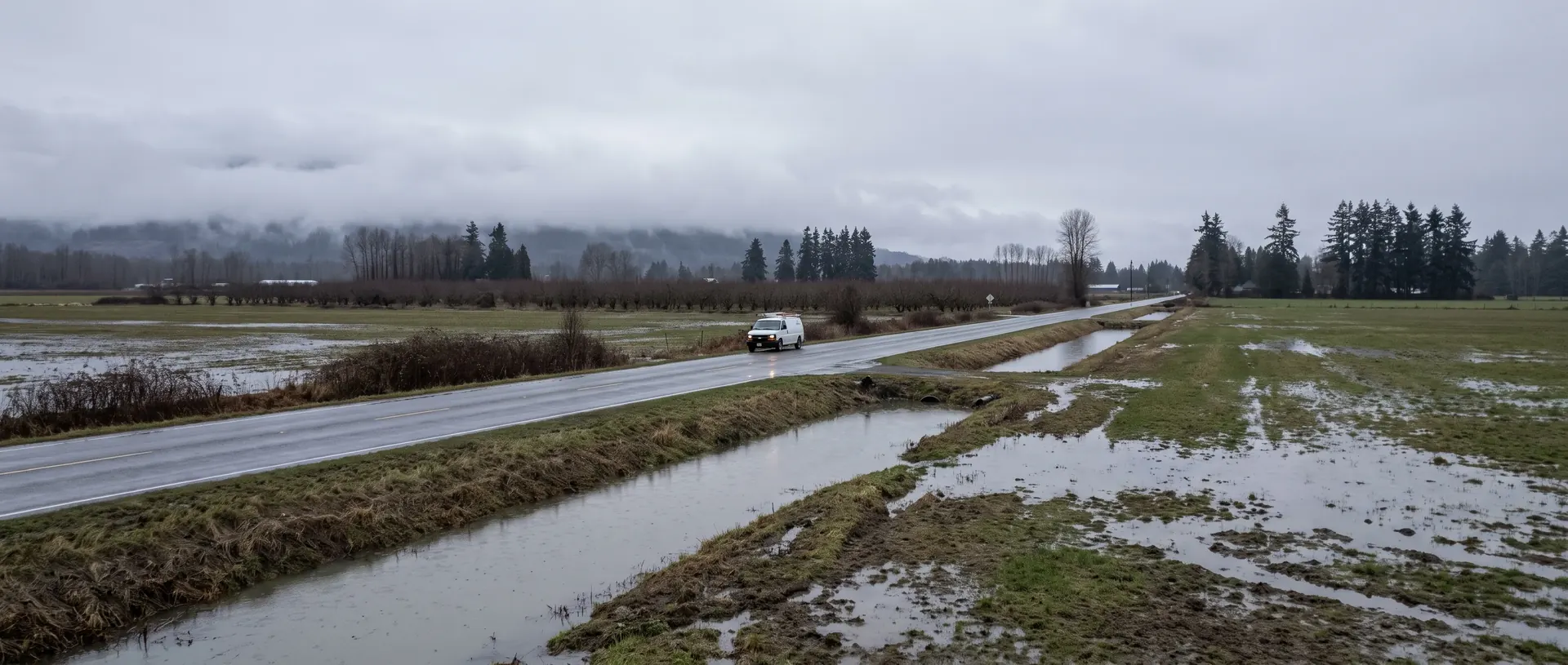 Work van on a rural road across Whatcom County farmland with low cloud on the foothills
